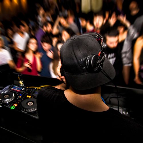 DJ with headphone and dj set at night club party. People at the