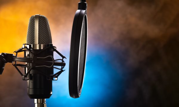 Professional studio microphone and pop filter on a beautiful yellow-blue smoky background. Night club, concert, radio broadcasting, television, recording studio, purity of sound, vocals, music.