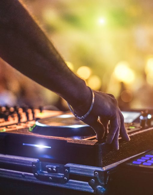 Dj mixing outdoor at beach party festival with crowd of people in background - Summer nightlife view of disco club outside - Soft focus on hand - Fun ,youth,entertainment and fest concept