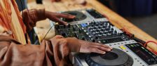 Hands of black man in casualwear standing by wooden table and creating new music and recording it for entertainment event