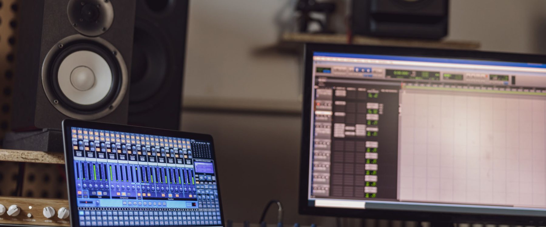 Close-up of switched on laptop and monitor screen on table in the sound engineer room in a broadcasting and recording studio